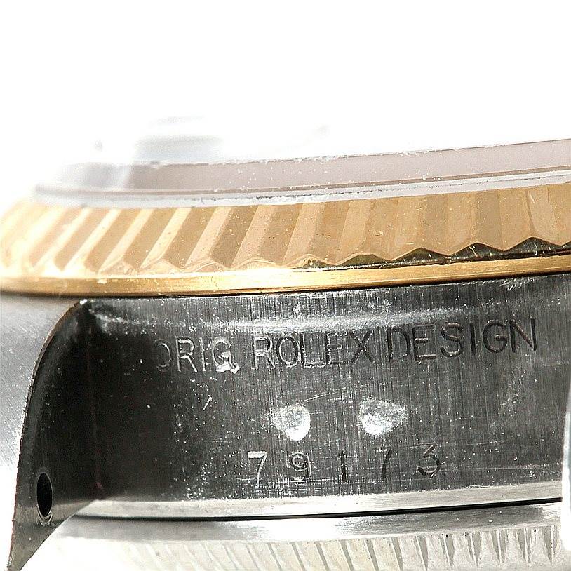 The image shows the side of a Rolex Datejust 79173 Women's Stainless Steel Blue Dial 79173 Women's Stainless Steel Blue Dial watch case, highlighting the engraved "ORIG ROLEX DESIGN" and part of the bezel.