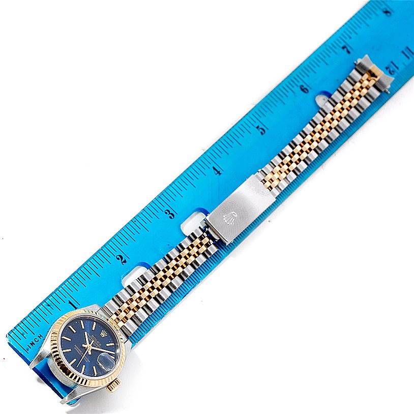 This image shows the Rolex Datejust 79173 Women's Stainless Steel Blue Dial 79173 Women's Stainless Steel Blue Dial watch laid flat, highlighting the face and the entire bracelet against a blue ruler.
