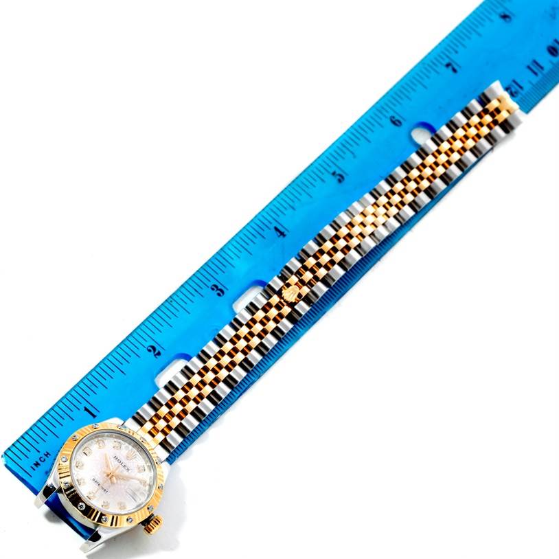 The Rolex Datejust 179313 Women
s Stainless Steel Beige Dial 179313 Women
s Stainless Steel Beige Dial watch is shown from a top-down angle, displaying its dial, bezel, and two-tone bracelet beside a blue ruler.