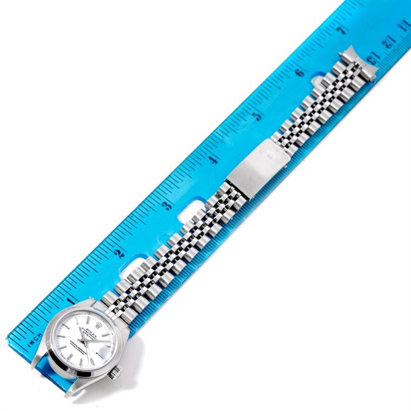 The image shows a Rolex Datejust 79160 Women's Stainless Steel White Dial 79160 Women's Stainless Steel White Dial watch viewed from above, with its bracelet extended and aligned beside a ruler.