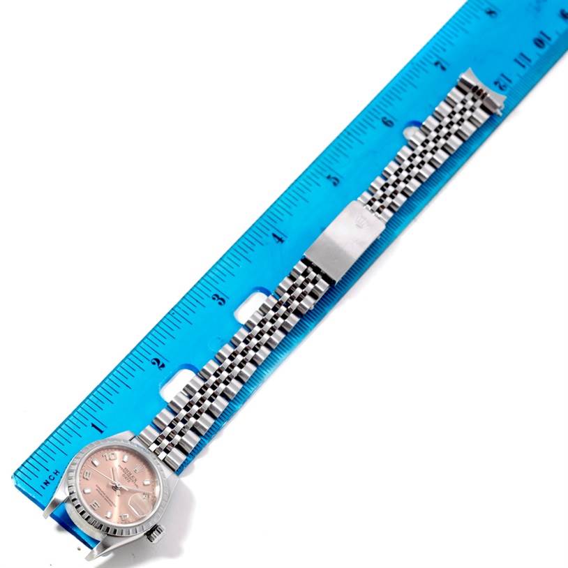 The Rolex Datejust 79160 Women's Stainless Steel Silver Dial 79160 Women's Stainless Steel Silver Dial watch is shown laid flat with its face, bezel, and bracelet visible next to a blue ruler.