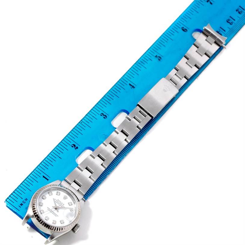 The Rolex Datejust 79174 Women's Stainless Steel White Dial 79174 Women's Stainless Steel White Dial watch is shown from a top-down angle with its bracelet extended alongside a blue ruler.