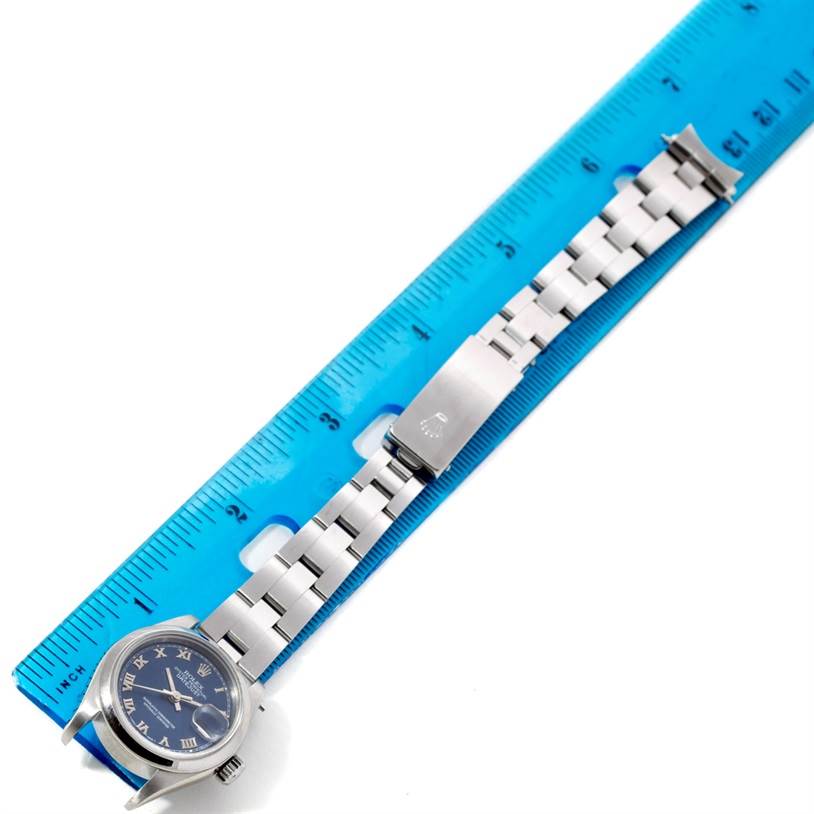 The Rolex Datejust 69160 Women
s Stainless Steel Blue Dial 69160 Women
s Stainless Steel Blue Dial watch is shown lying flat next to a ruler, displaying its entire band and face.