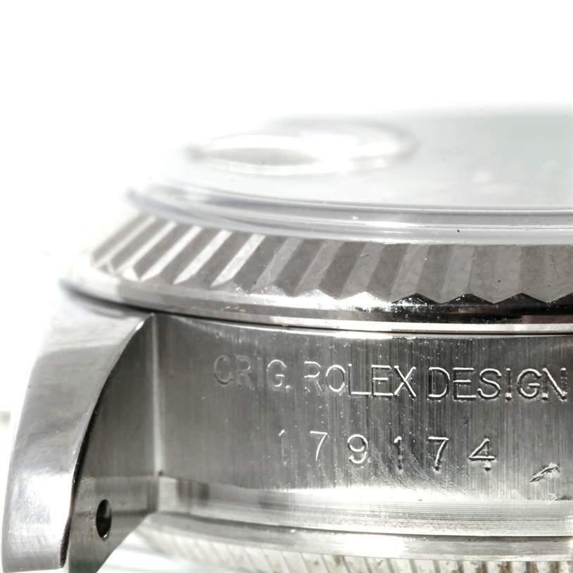This close-up of a Rolex Datejust 179174 Women's Stainless Steel Mother of Pearl Dial 179174 Women's Stainless Steel Mother of Pearl Dial watch shows the side of the case, features the crown, and includes serial number engravings.