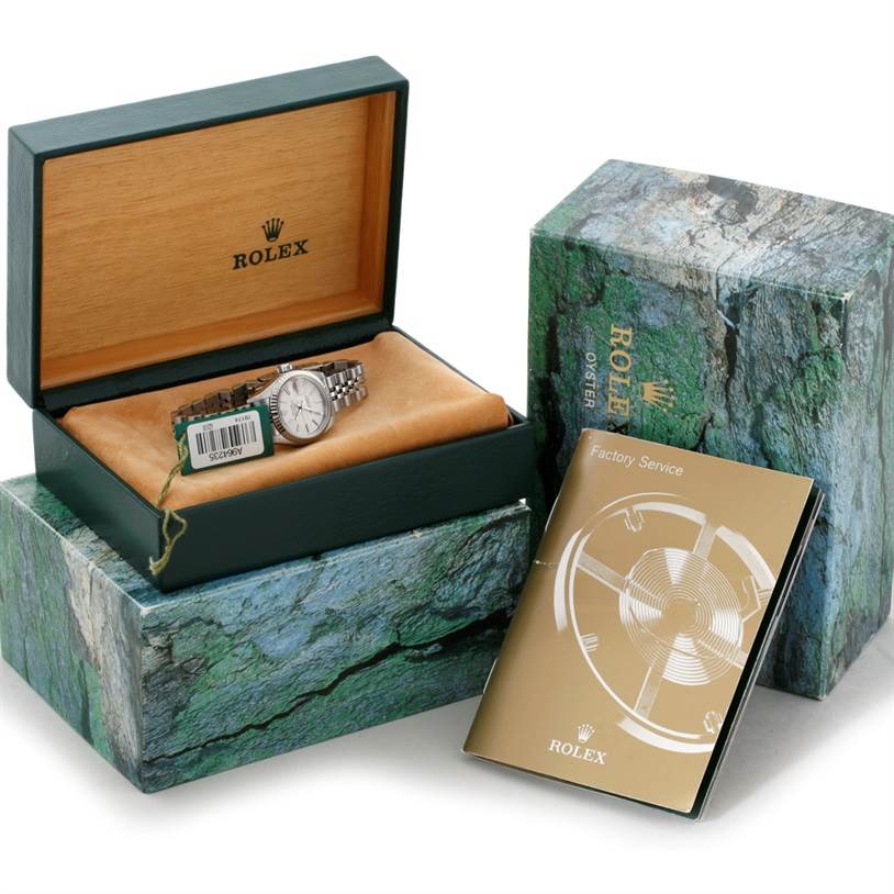 This image shows a Rolex Datejust 79174 Women's Stainless Steel Silver Dial 79174 Women's Stainless Steel Silver Dial watch in its open box, along with additional packaging and a factory service manual.
