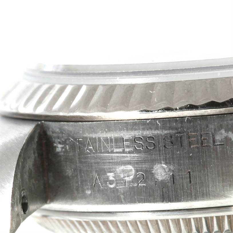 The image shows a close-up of the side case and edge of the bezel of a Rolex Datejust 79174 Women's Stainless Steel Mother of Pearl Dial 79174 Women's Stainless Steel Mother of Pearl Dial watch, highlighting its stainless steel material and serial engraving.