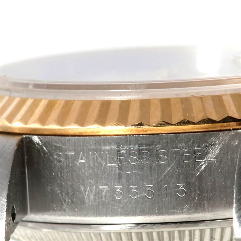 Close-up of the side of a Rolex Datejust 69173 Women
s Stainless Steel White Dial 69173 Women
s Stainless Steel White Dial watch showing part of the gold bezel and stainless steel case with engravings.