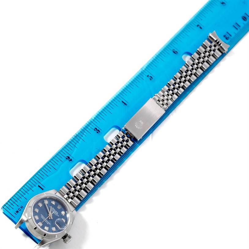 The image shows a Rolex Datejust 79190 Women's Stainless Steel Blue Dial 79190 Women's Stainless Steel Blue Dial watch positioned along a blue ruler, with a full view of the dial and bracelet.