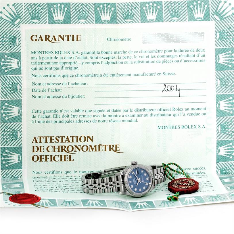 The image shows a Rolex Datejust 79190 Women's Stainless Steel Blue Dial 79190 Women's Stainless Steel Blue Dial watch placed on its warranty card and certificate, along with the official seal.