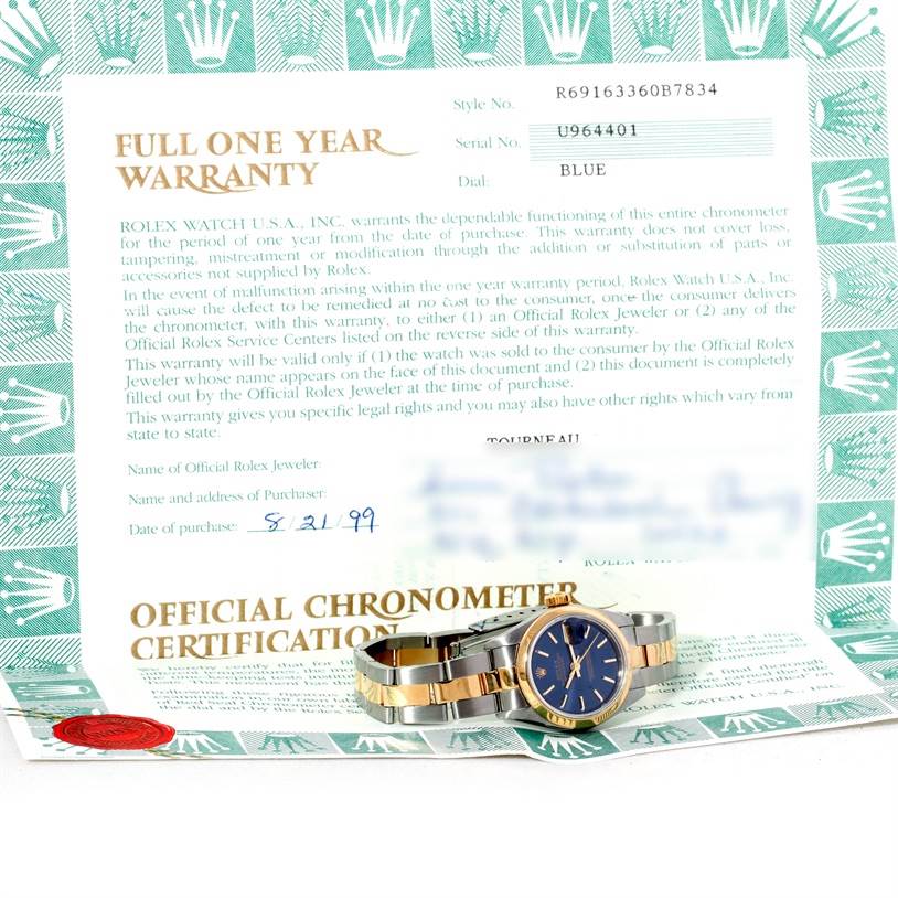 The image shows a Rolex Datejust 69163 Women's Stainless Steel Blue Dial 69163 Women's Stainless Steel Blue Dial watch, photographed from a low angle alongside its warranty and certification documents.