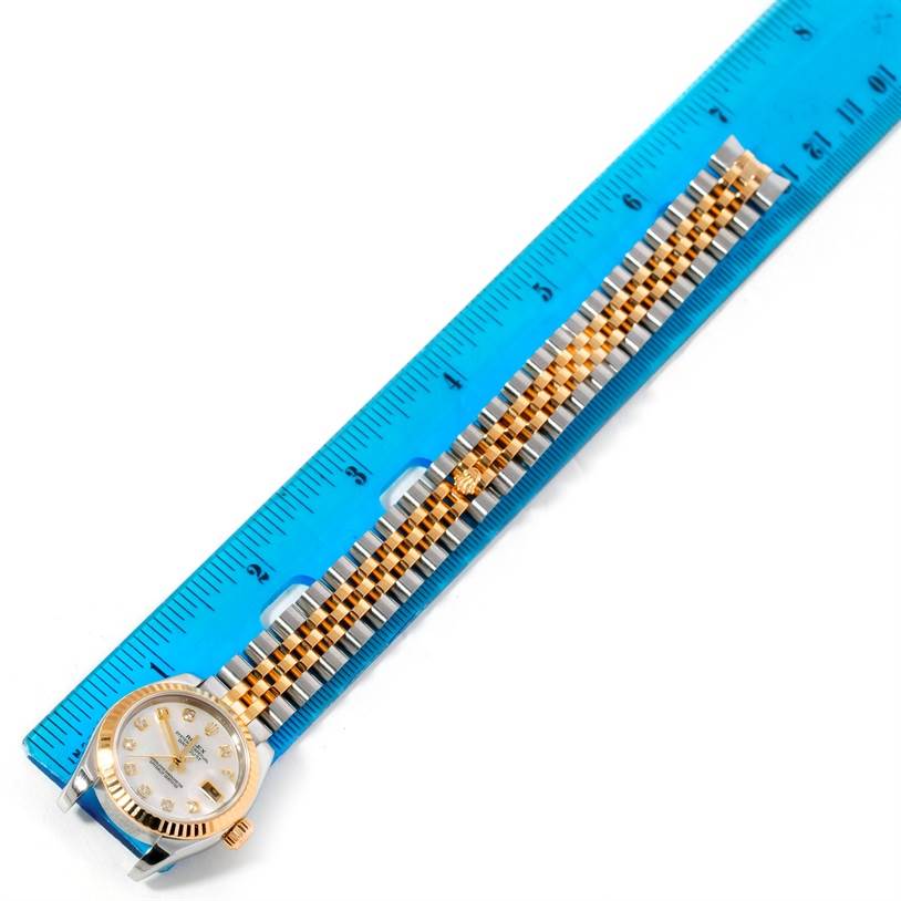 The image shows a Rolex Datejust 179173 Women's Steel and Gold (two tone) Mother of Pearl Dial 179173 Women's Steel and Gold (two tone) Mother of Pearl Dial watch angled flat against a ruler, displaying its dial and two-tone bracelet.