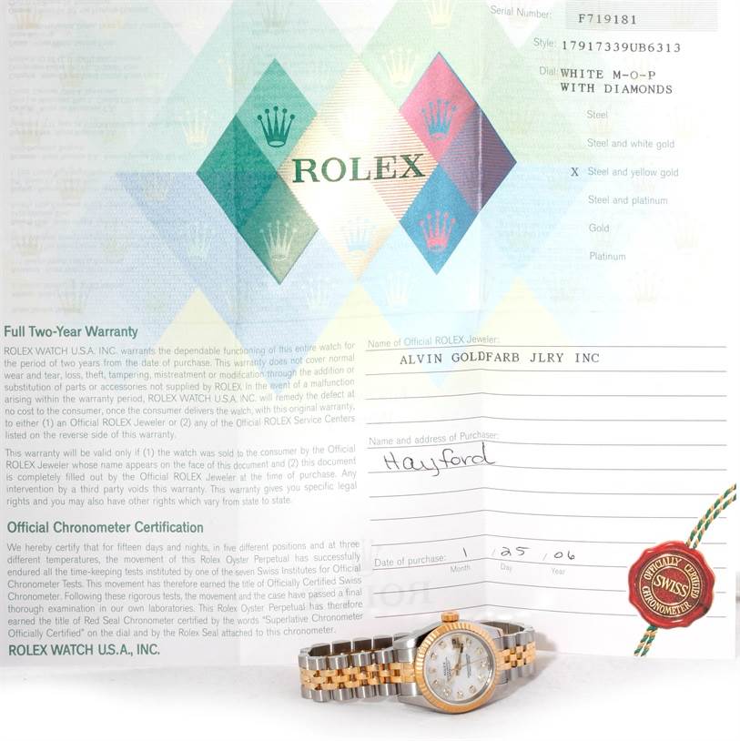 The image shows a Rolex Datejust 179173 Women's Steel and Gold (two tone) Mother of Pearl Dial 179173 Women's Steel and Gold (two tone) Mother of Pearl Dial watch at a slight angled view, alongside its warranty and certification papers.