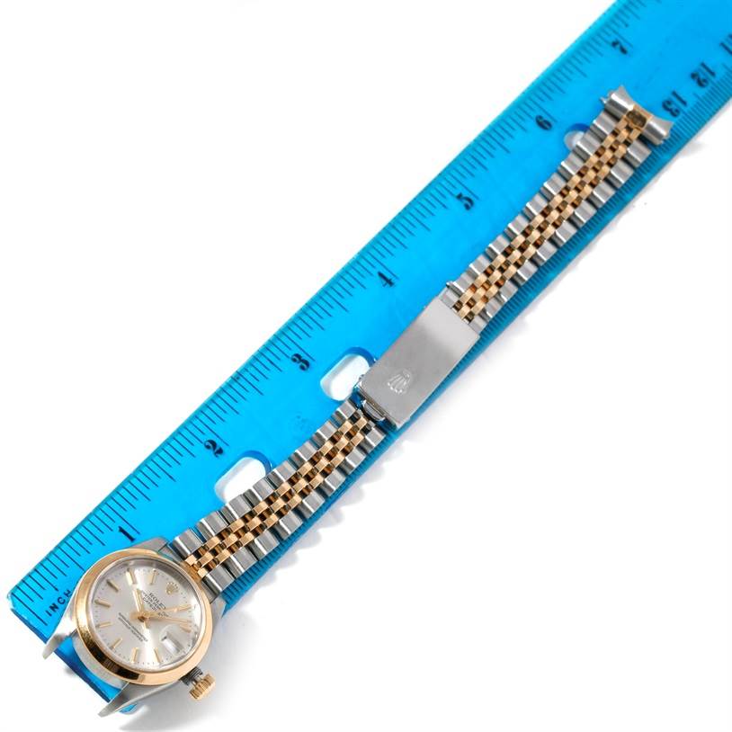 The Rolex Datejust 69173 Women's Stainless Steel Silver Dial 69173 Women's Stainless Steel Silver Dial watch is shown from a top-down angle, including the face, bracelet, and clasp, placed next to a blue ruler.