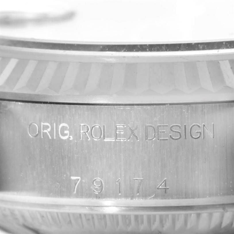 This is a close-up angle of the case side of a Rolex Datejust 79174 Women's Stainless Steel Blue Dial 79174 Women's Stainless Steel Blue Dial, showcasing the engravings "ORIG. ROLEX DESIGN" and the serial number "79174."