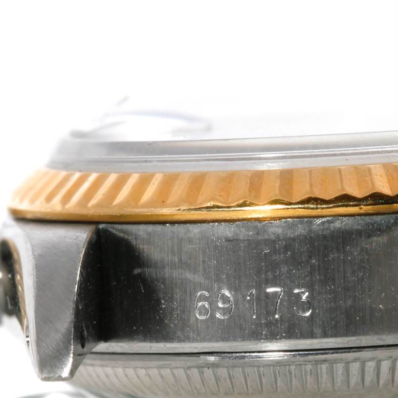This is a close-up of the side of a Rolex Datejust 69173 Women
s Stainless Steel Beige Dial 69173 Women
s Stainless Steel Beige Dial watch, showcasing the bezel and part of the case with a partial serial number.