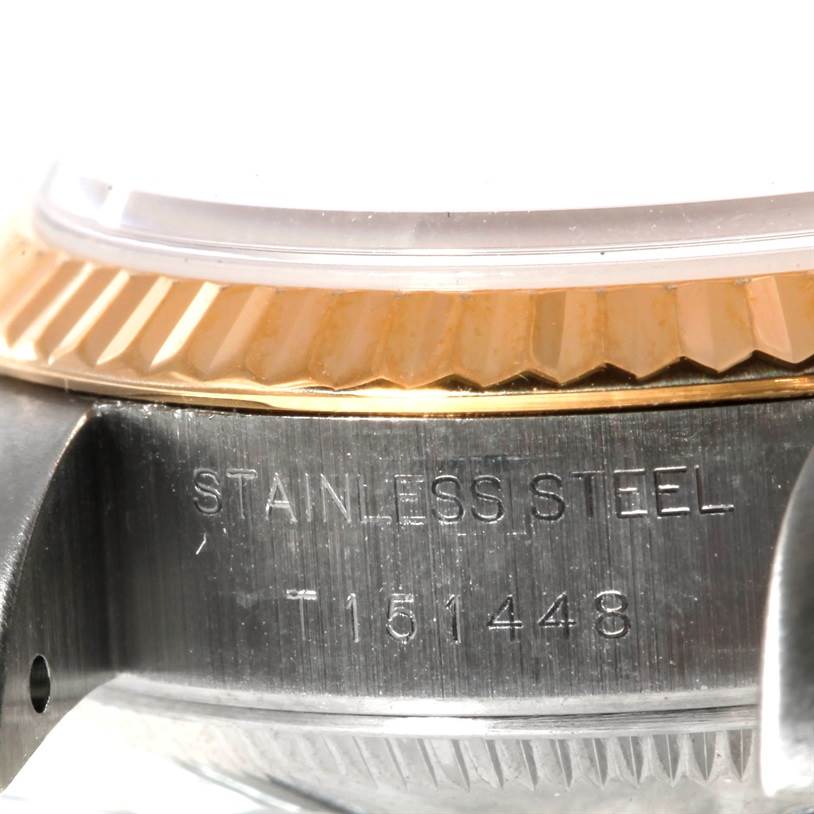 This close-up image shows the stainless steel case and gold fluted bezel of a Rolex Datejust 69173 Women's Stainless Steel Champagne Dial 69173 Women's Stainless Steel Champagne Dial watch, including some engraved text.