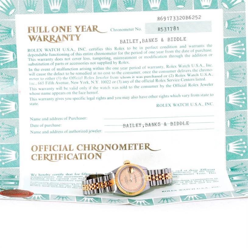 The Rolex Datejust 69173 Women's Stainless Steel Champagne Dial 69173 Women's Stainless Steel Champagne Dial watch is shown from a front angle, resting on its official chronometer certification and warranty document.