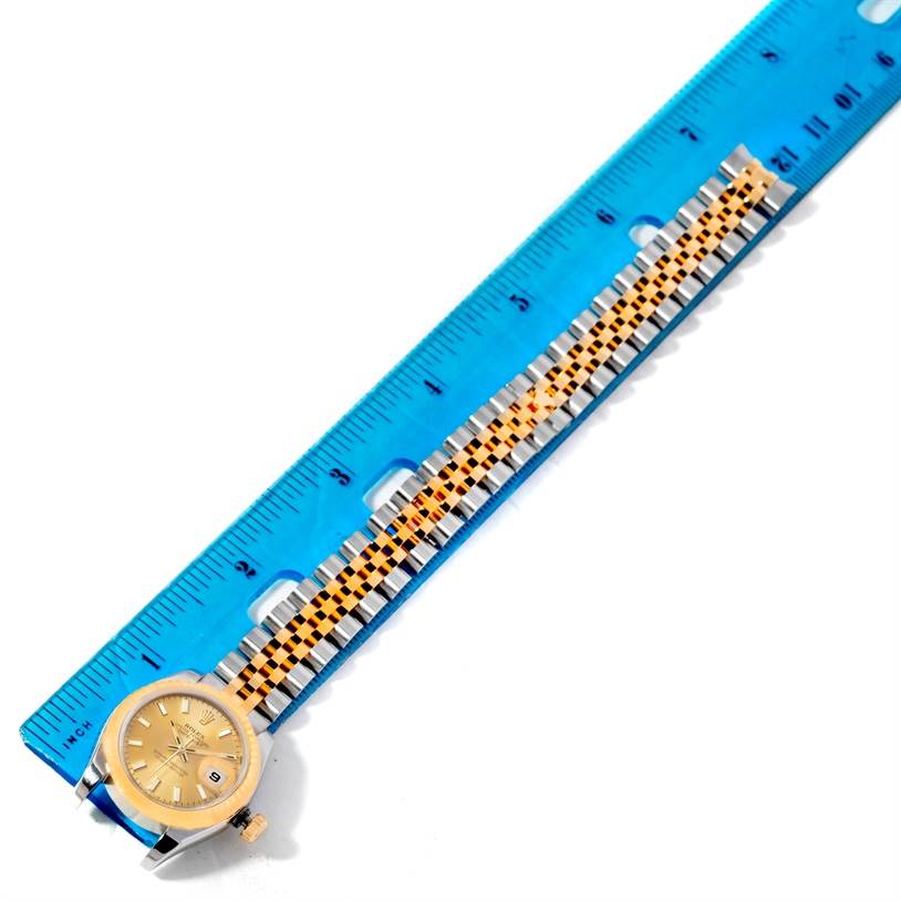 The Rolex Datejust 179173 Women's Steel and Gold (two tone) Champagne Dial 179173 Women's Steel and Gold (two tone) Champagne Dial watch is displayed flat, showing the full bracelet and dial next to a blue ruler for measurement.