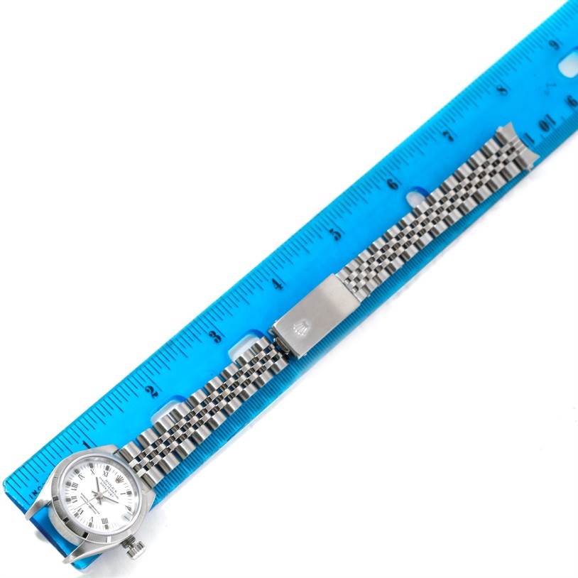 The Rolex Datejust 79190 Women's Stainless Steel White Dial 79190 Women's Stainless Steel White Dial watch is shown in a top-down view with its bracelet extended alongside a blue ruler for measurement.