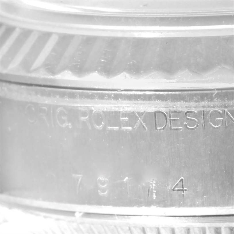 Close-up view of the side of a Rolex Datejust 79174 Women's Stainless Steel Blue Dial 79174 Women's Stainless Steel Blue Dial watch showing the engraved "ORIG. ROLEX DESIGN" and part of the serial number.