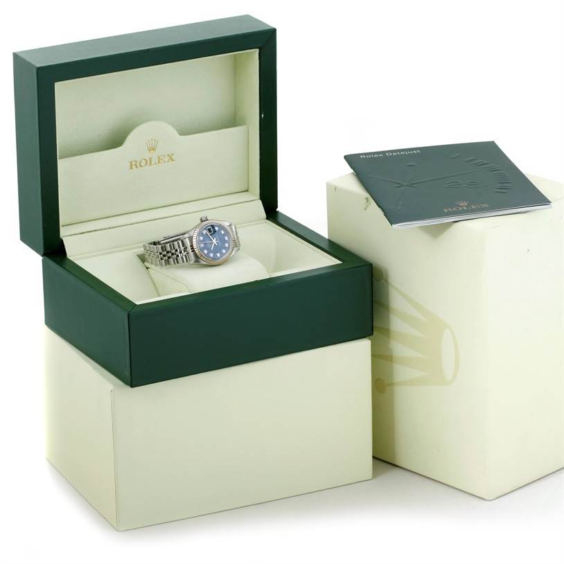 The Rolex Datejust 79174 Women's Stainless Steel Blue Dial 79174 Women's Stainless Steel Blue Dial watch is displayed in an open green and beige box with a manual on the side.