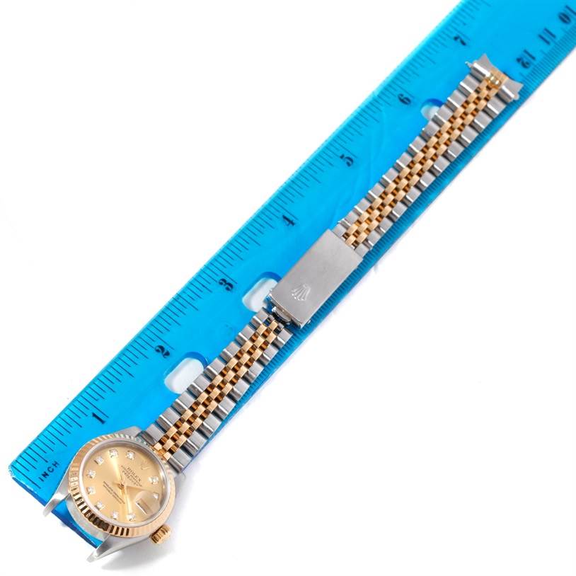 The image shows a Rolex Datejust 79173 Women's Stainless Steel Champagne Dial 79173 Women's Stainless Steel Champagne Dial watch lying flat beside a blue ruler, displaying the watch face, bracelet, and clasp.