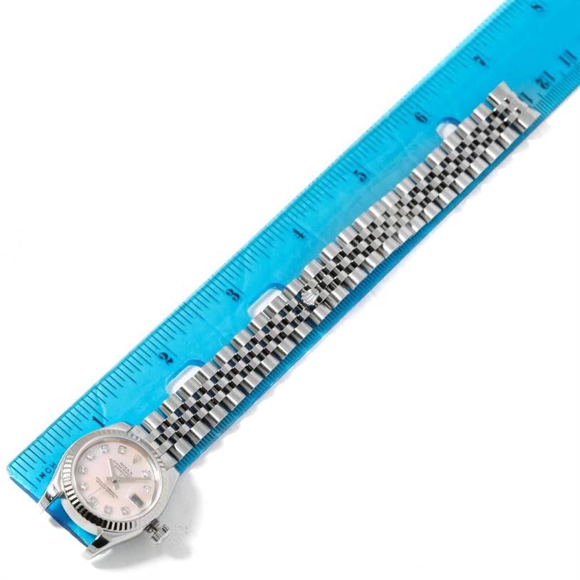 The Rolex Datejust 179174 Women's Stainless Steel Mother of Pearl Dial 179174 Women's Stainless Steel Mother of Pearl Dial watch is shown from an aerial perspective, displaying the face, bezel, and bracelet against a blue ruler.