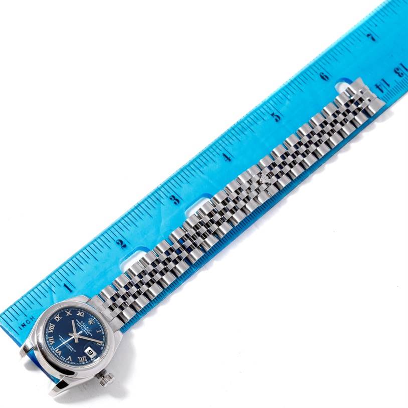 The image shows a Rolex Datejust 179160 Women's Stainless Steel Blue Dial 179160 Women's Stainless Steel Blue Dial watch laid flat against a blue ruler, highlighting the dial and jubilee bracelet.