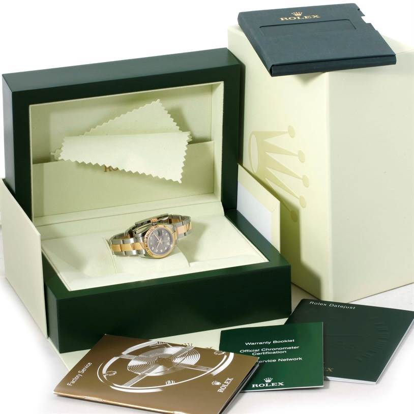 The Rolex Datejust 179173 Women's Steel and Gold (two tone) Grey Dial 179173 Women's Steel and Gold (two tone) Grey Dial watch and its accessories are displayed inside an open box, alongside several booklets and a cleaning cloth.