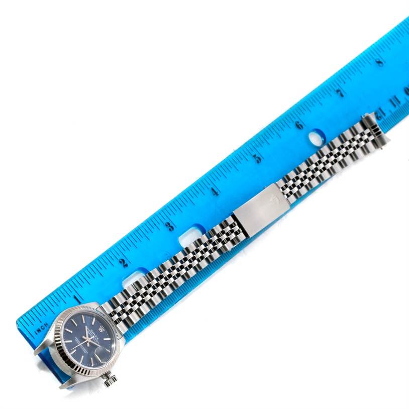 This image shows a Rolex Datejust 79174 Women
s Stainless Steel Blue Dial 79174 Women
s Stainless Steel Blue Dial watch laid flat next to a ruler, displaying the full band and face.