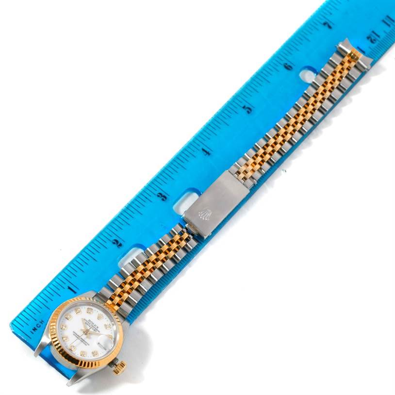 The image shows a Rolex Datejust 69173 Women's Stainless Steel White Dial 69173 Women's Stainless Steel White Dial watch lying flat with its face, bezel, bracelet, and clasp visible, next to a blue ruler for scale.