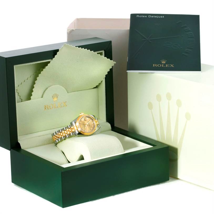 The image shows a Rolex Datejust 179173 Women's Steel and Gold (two tone) Champagne Dial 179173 Women's Steel and Gold (two tone) Champagne Dial watch in a green box with a booklet, cleaning cloth, and cushion.
