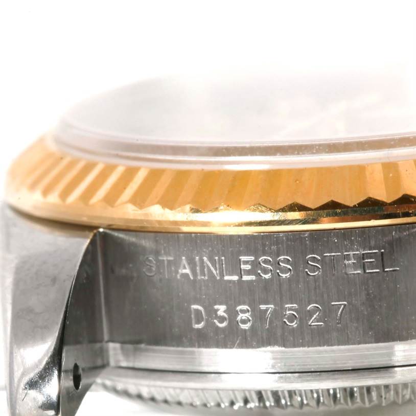 The image shows a close-up side angle of a Rolex Datejust 179173 Women's Steel and Gold (two tone) Champagne Dial 179173 Women's Steel and Gold (two tone) Champagne Dial's case and bezel, with "STAINLESS STEEL" and a serial number engraved.