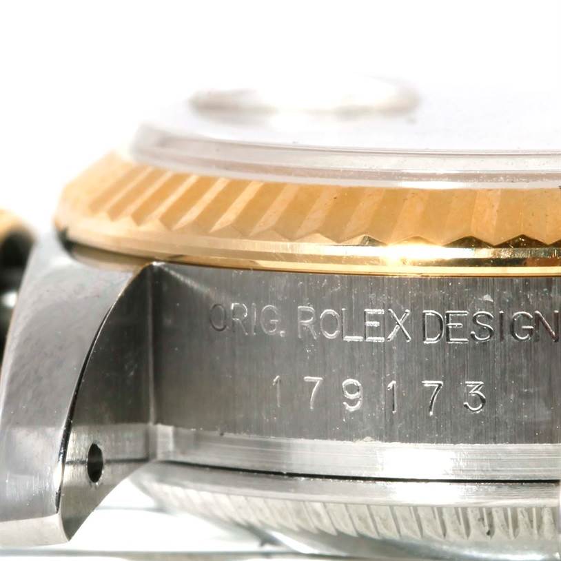 This is an angled close-up of a Rolex Datejust 179173 Women's Steel and Gold (two tone) Champagne Dial 179173 Women's Steel and Gold (two tone) Champagne Dial watch, showing the side of the case with engraved text and part of the fluted bezel.