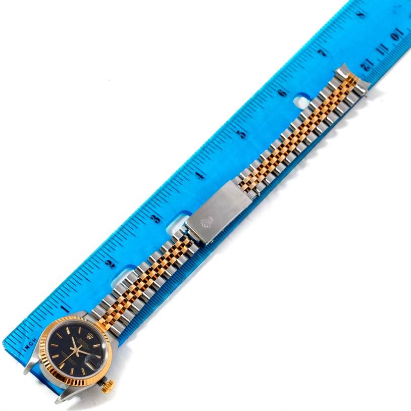 The Rolex Datejust 69173 Women's Stainless Steel Black Dial 69173 Women's Stainless Steel Black Dial watch is shown laid flat with a ruler for scale, highlighting the face, case, and bracelet.