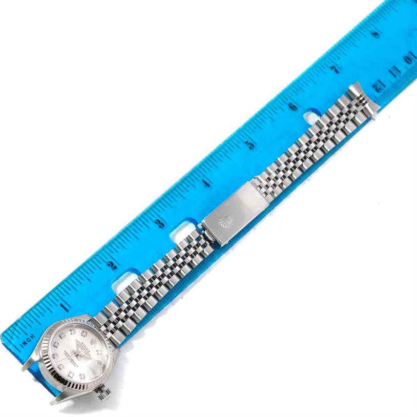 The image shows a laid-flat Rolex Datejust 79174 Women's Stainless Steel Silver Dial 79174 Women's Stainless Steel Silver Dial watch with the face and bracelet clasp prominently displayed, alongside a blue ruler for scale.