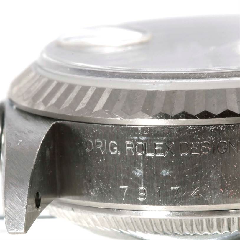 This image shows a close-up side view of a Rolex Datejust 79174 Women's Stainless Steel Silver Dial 79174 Women's Stainless Steel Silver Dial watch, highlighting the bezel, crystal, and part of the case with engravings.