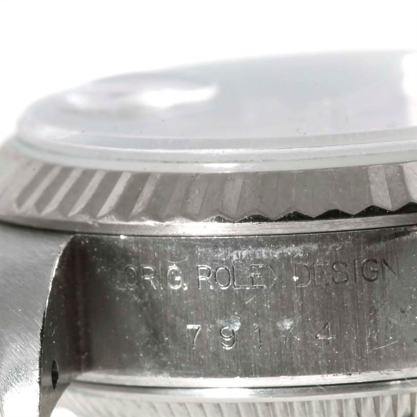 The image shows a close-up of the side view of the Rolex Datejust 79174 Women's Stainless Steel Silver Dial 79174 Women's Stainless Steel Silver Dial watch, highlighting the case and the engraved serial number.
