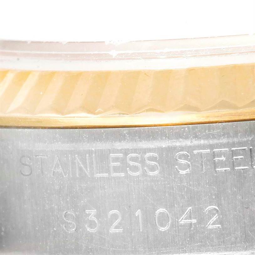 The image shows a close-up of the side of a Rolex Datejust 69173 Women's Stainless Steel Champagne Dial 69173 Women's Stainless Steel Champagne Dial watch, highlighting the fluted bezel and stainless steel case with an inscription.