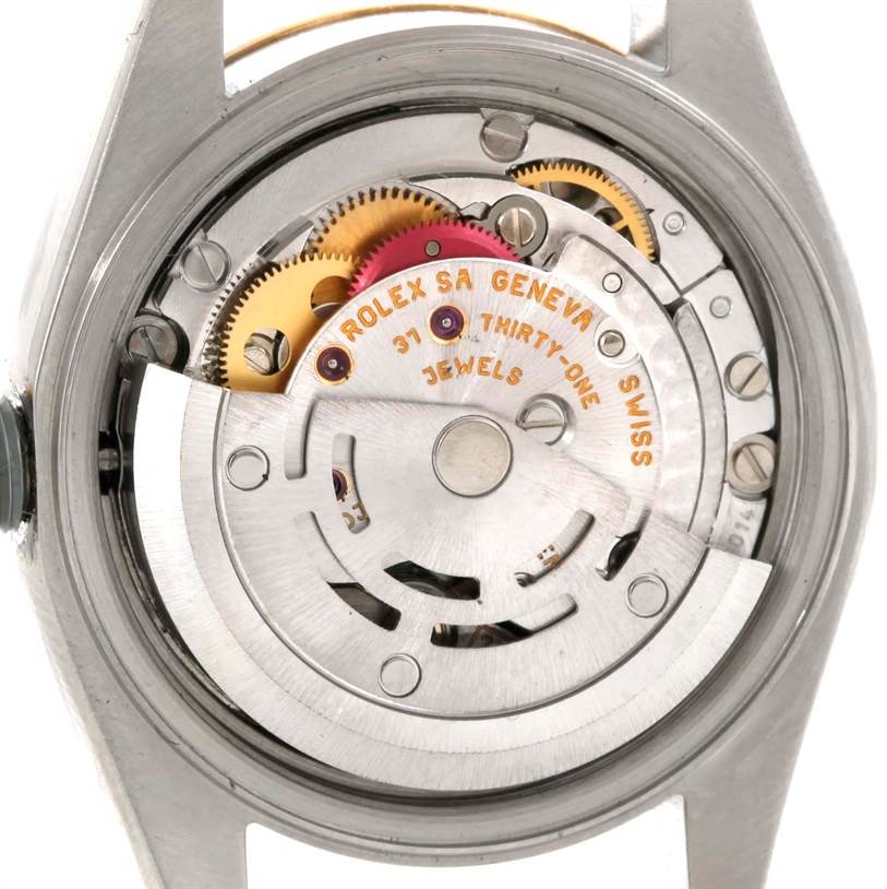 The image shows the inner mechanism of the Datejust model by Rolex, viewed from the back with gears and jewels visible.