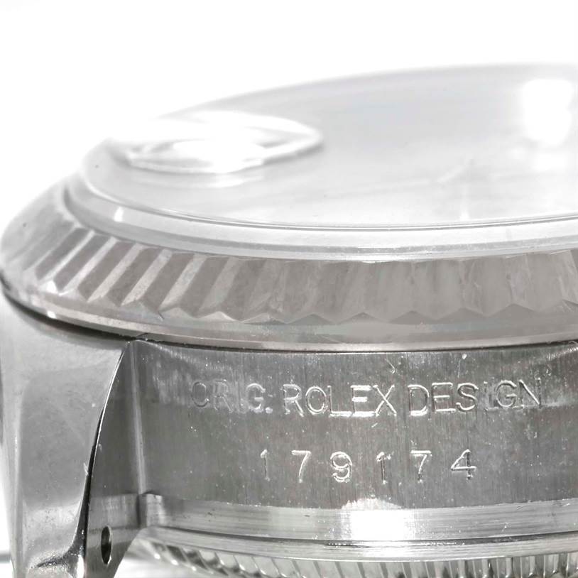 The image shows a close-up side view of the Rolex Datejust 179174 Women's Stainless Steel White Dial 179174 Women's Stainless Steel White Dial watch, featuring the fluted bezel and engraved model number 179174.