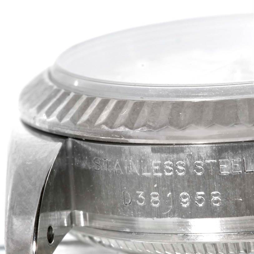 The image shows a close-up of the side of a Rolex Datejust 179174 Women's Stainless Steel White Dial 179174 Women's Stainless Steel White Dial watch, highlighting the fluted bezel and part of the case with the serial number.