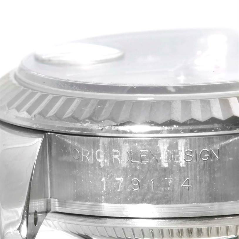 The image shows a close-up side angle of a Rolex Datejust 179174 Women's Stainless Steel Mother of Pearl Dial 179174 Women's Stainless Steel Mother of Pearl Dial, highlighting the fluted bezel and engraved serial number.
