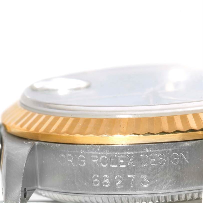 The image shows a close-up side view of a Rolex Mid-Size 68273 Women's Steel and Gold (two tone) Blue Dial 68273 Women's Steel and Gold (two tone) Blue Dial model, highlighting the bezel and part of the case with the engraving.