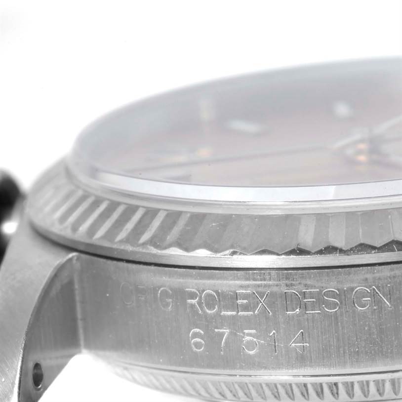 This close-up angle of the Mid-Size Rolex watch displays part of the case and the bezel with the serial number and "ROLEX DESIGN" engraving.