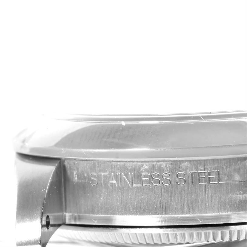 The photo shows a close-up side view of the stainless steel case of a mid-size Rolex watch.