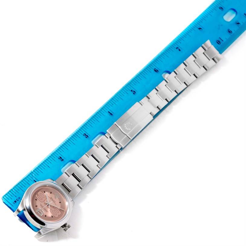 The Rolex Mid-Size 177200 Women's Stainless Steel Pink Dial 177200 Women's Stainless Steel Pink Dial watch is displayed horizontally with its entire band laid flat, next to a blue ruler for size reference.