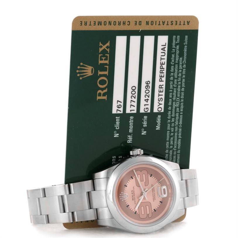 This image shows a Rolex Mid-Size 177200 Women's Stainless Steel Pink Dial 177200 Women's Stainless Steel Pink Dial Oyster Perpetual watch with a pink dial, alongside its official Rolex warranty card.