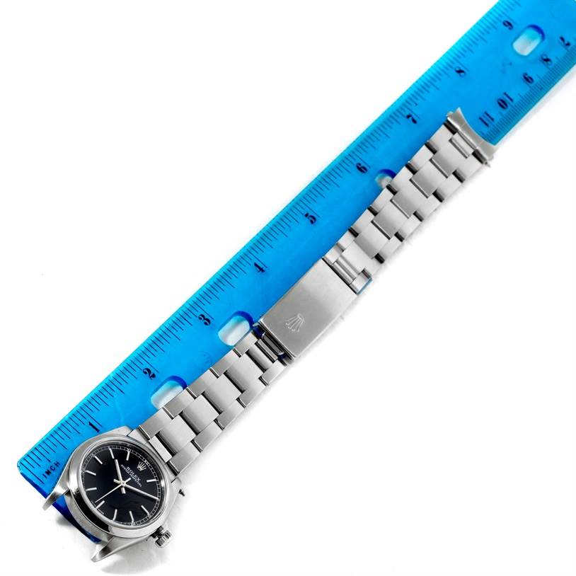 The image shows the Rolex Mid-Size 77080 Women's Stainless Steel Black Dial 77080 Women's Stainless Steel Black Dial watch from a top view, displaying the face, bracelet, and clasp alongside a ruler for scale.