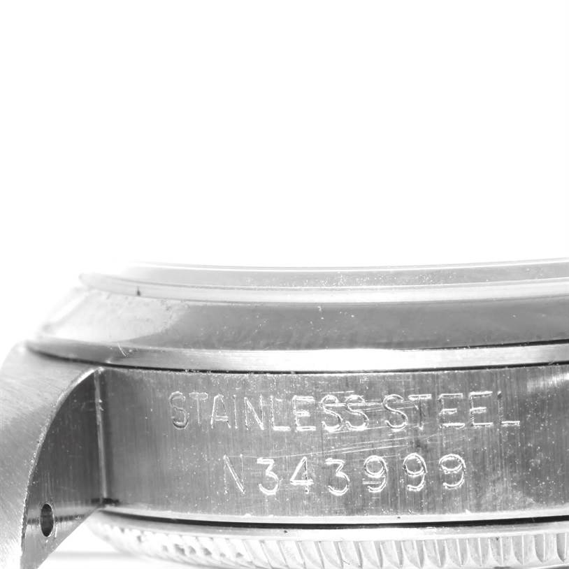 The image shows a side view of the bezel and case of the Rolex Mid-Size 67480 Women's Stainless Steel Black Dial 67480 Women's Stainless Steel Black Dial model, featuring the words "STAINLESS STEEL" and a serial number.